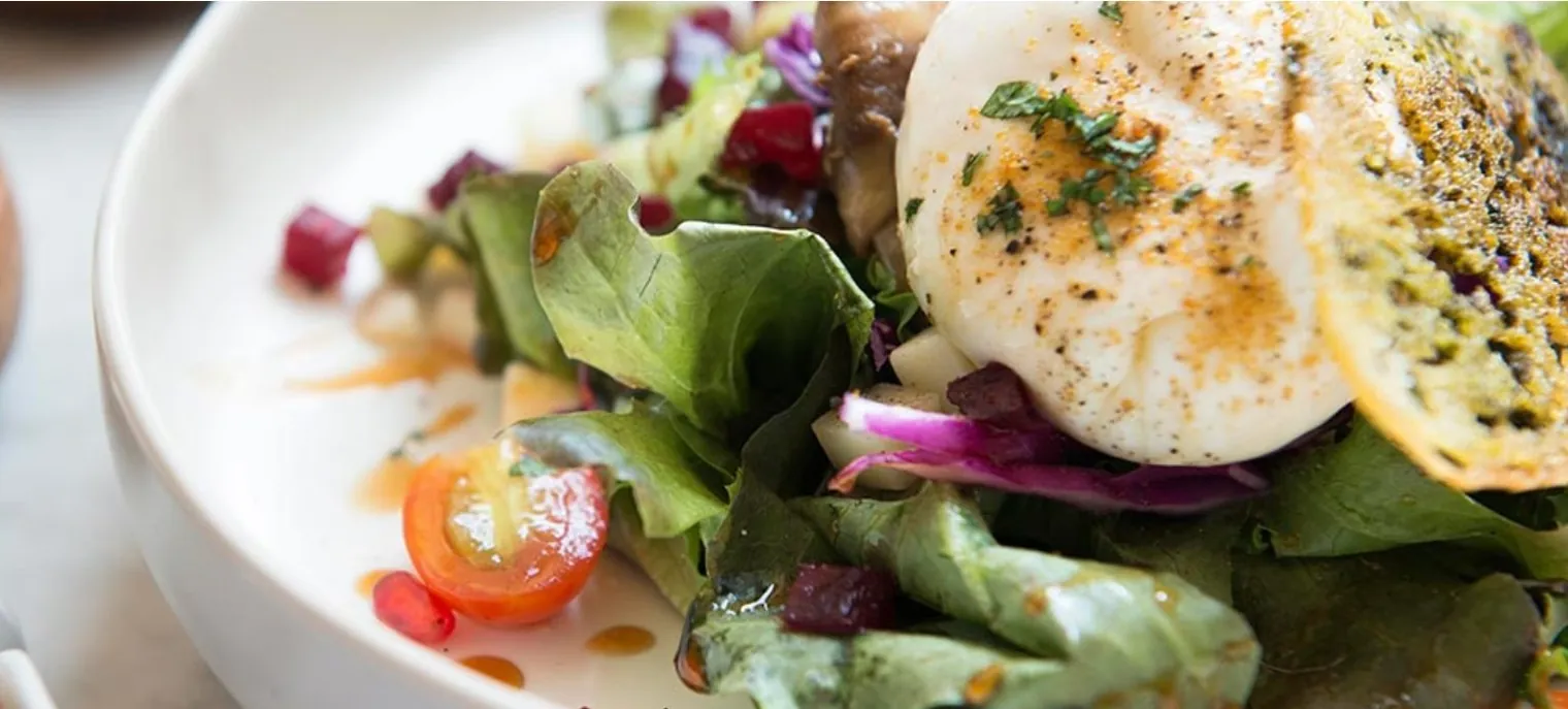 A plated Thai salad with a poached egg, tomato and leaves