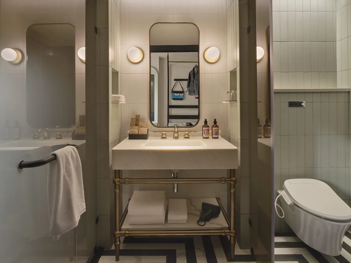 Suite bathroom with a brass-framed washstand, a freestanding tub and a black-and-white chevron floor