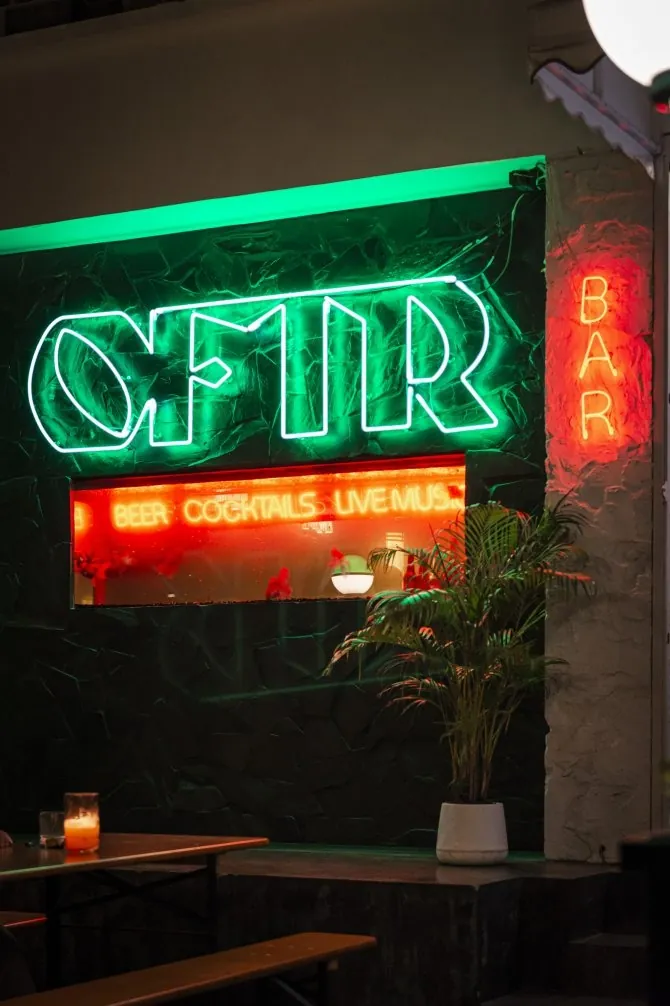 The neon OFTR Bar sign glowing above the entrance to the bar