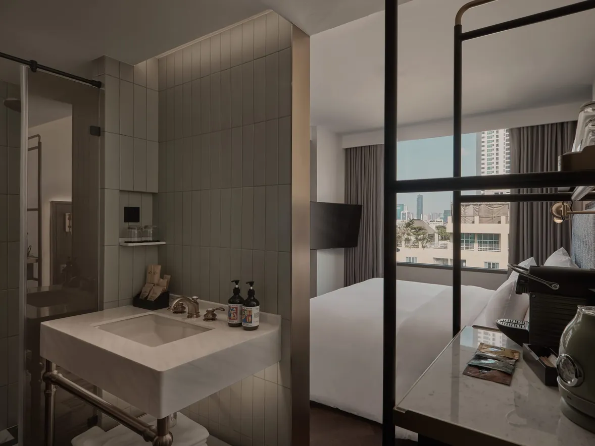 Washstand behind a glazed partition, with the bed and city window beyond