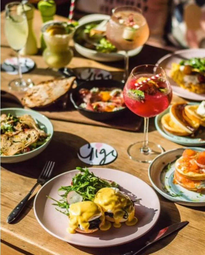 A table spread of shared plates and cocktails at Gigi Dining Hall, Bangkok