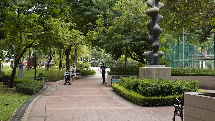 A shaded walking path and a sculpture among trees in Benchasiri Park, Bangkok