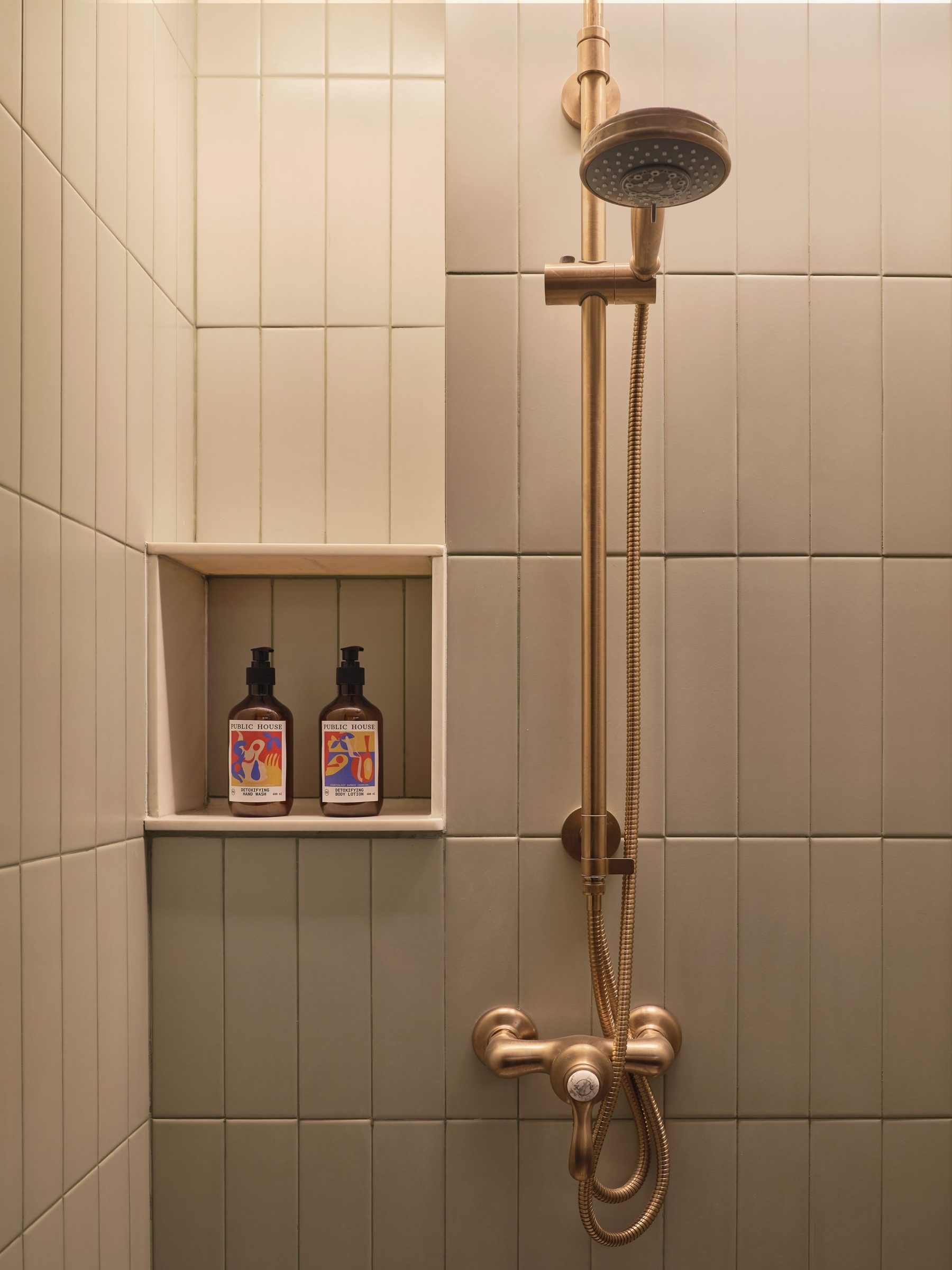 Walk-in rain shower with brass fittings and a tiled niche in the adjoining Uptown Room of a Two-Bedroom Suite