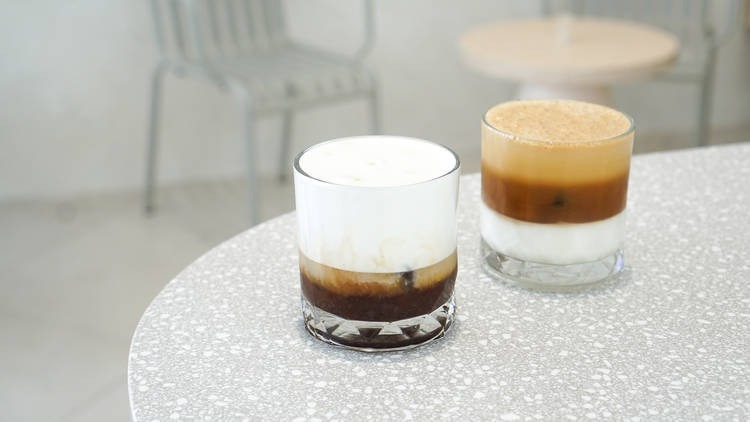 Two layered coffee drinks in glasses on a terrazzo table at PAGA Microroastery