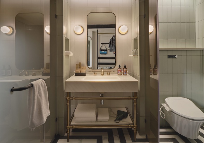 Bathroom vanity with a round mirror and globe lights at Public House Bangkok