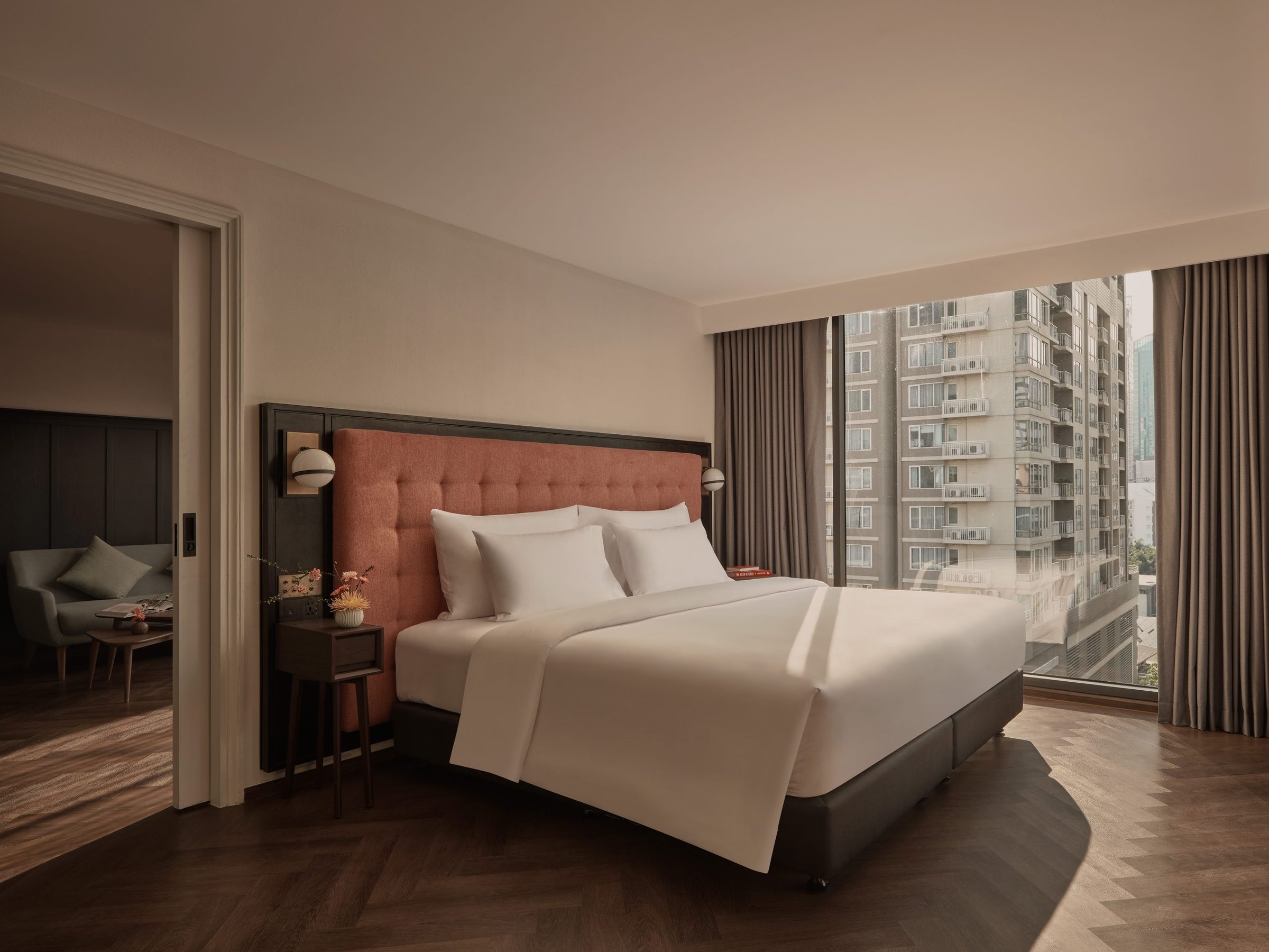 Bedroom with a terracotta headboard opening through to the living room