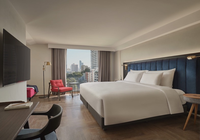 Day Dreamer Room with a bed, wall-mounted Smart TV, red chair and a window over Bangkok