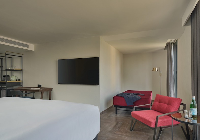 Wall-mounted Smart TV, writing desk and two red armchairs in a Day Dreamer Room