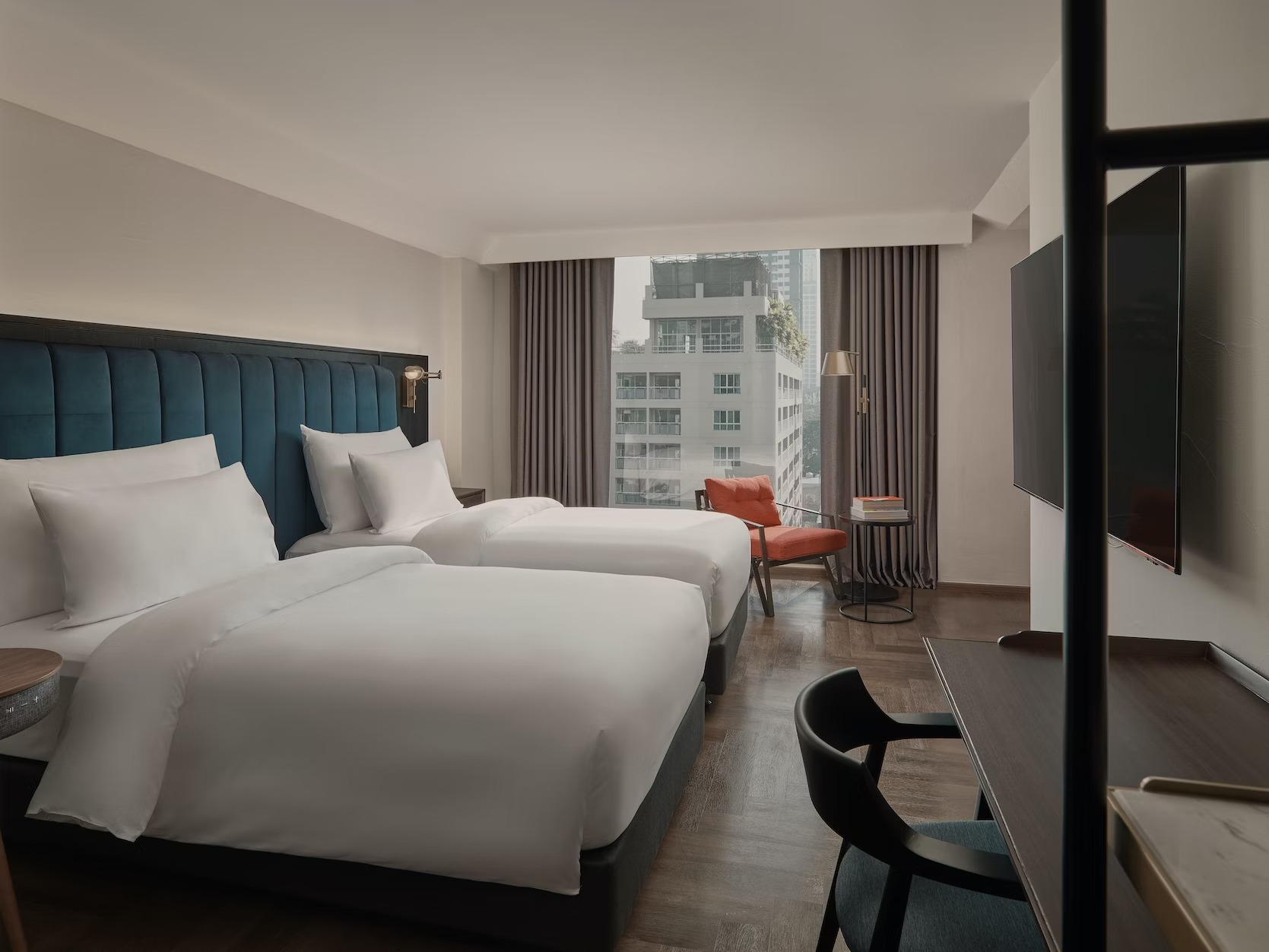 Twin beds with a teal headboard and a window over the city