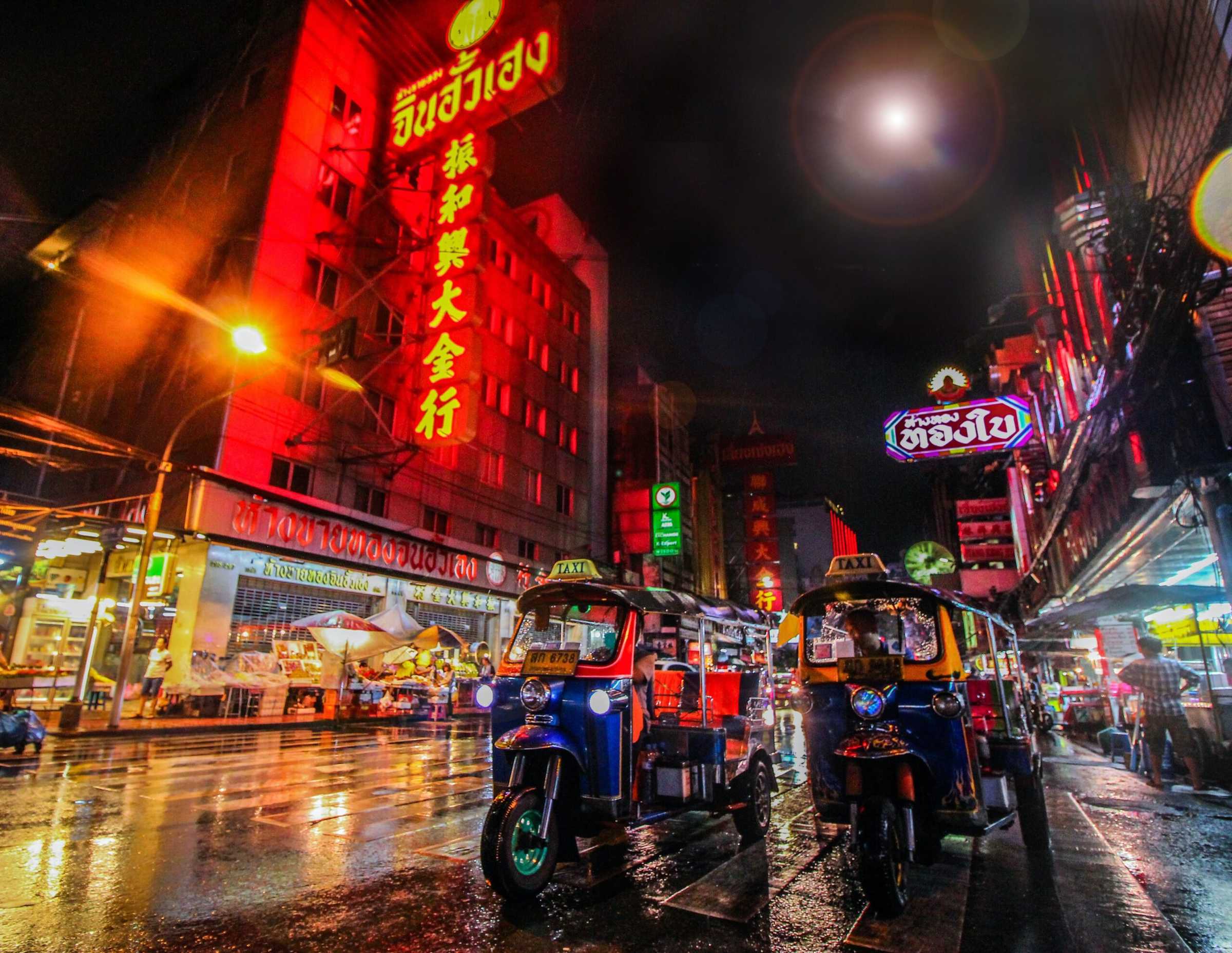 Neon shop signs above a Bangkok street at night