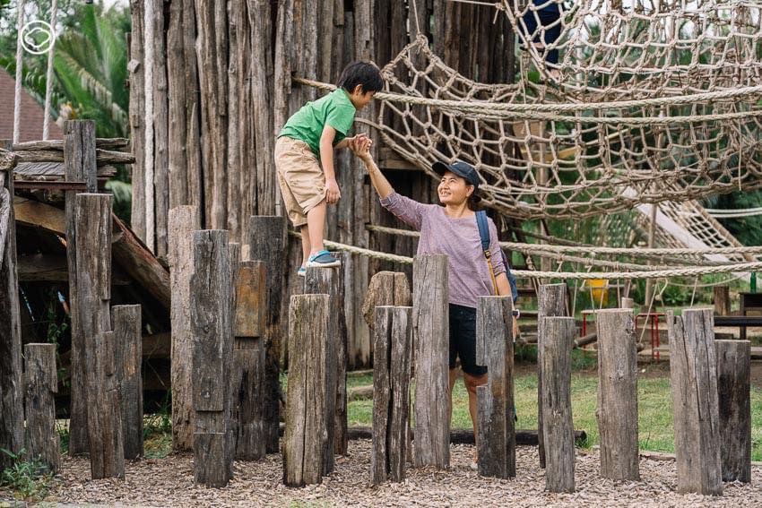 Children climbing a rope net in a wooden outdoor playground