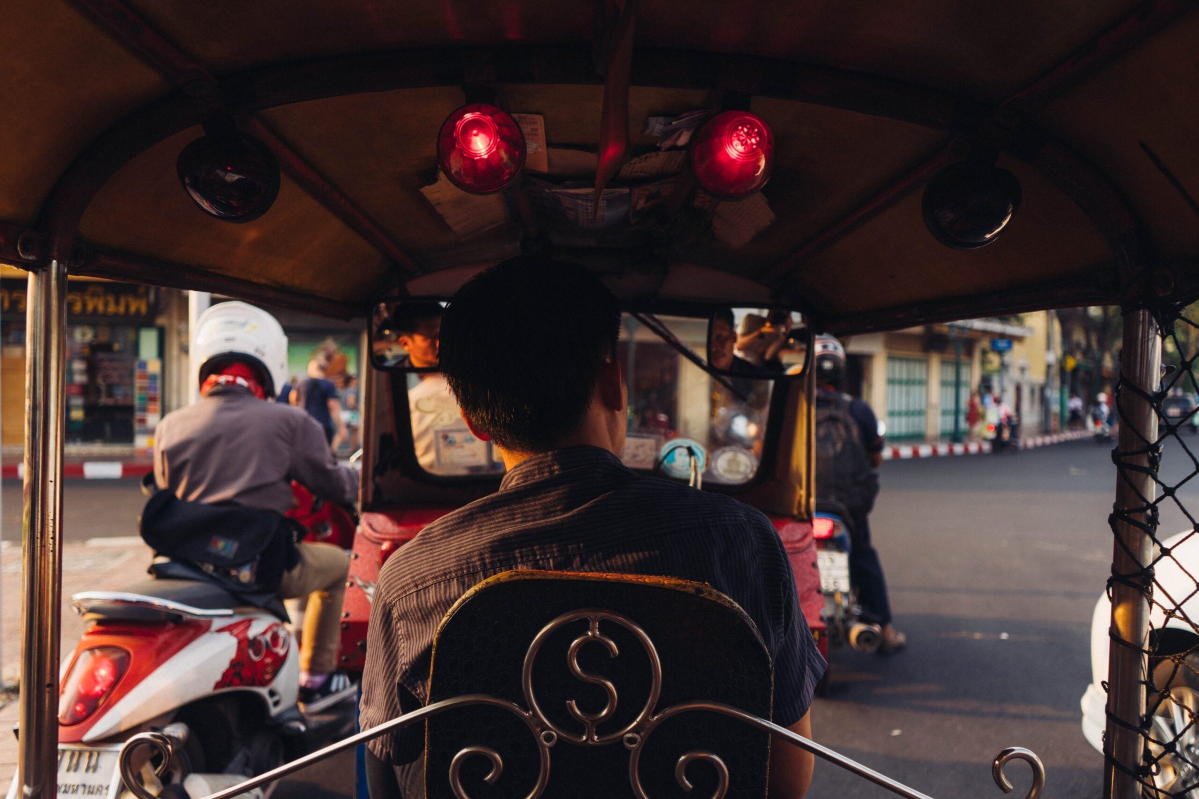 A passenger riding pillion on a motorbike taxi through Bangkok traffic