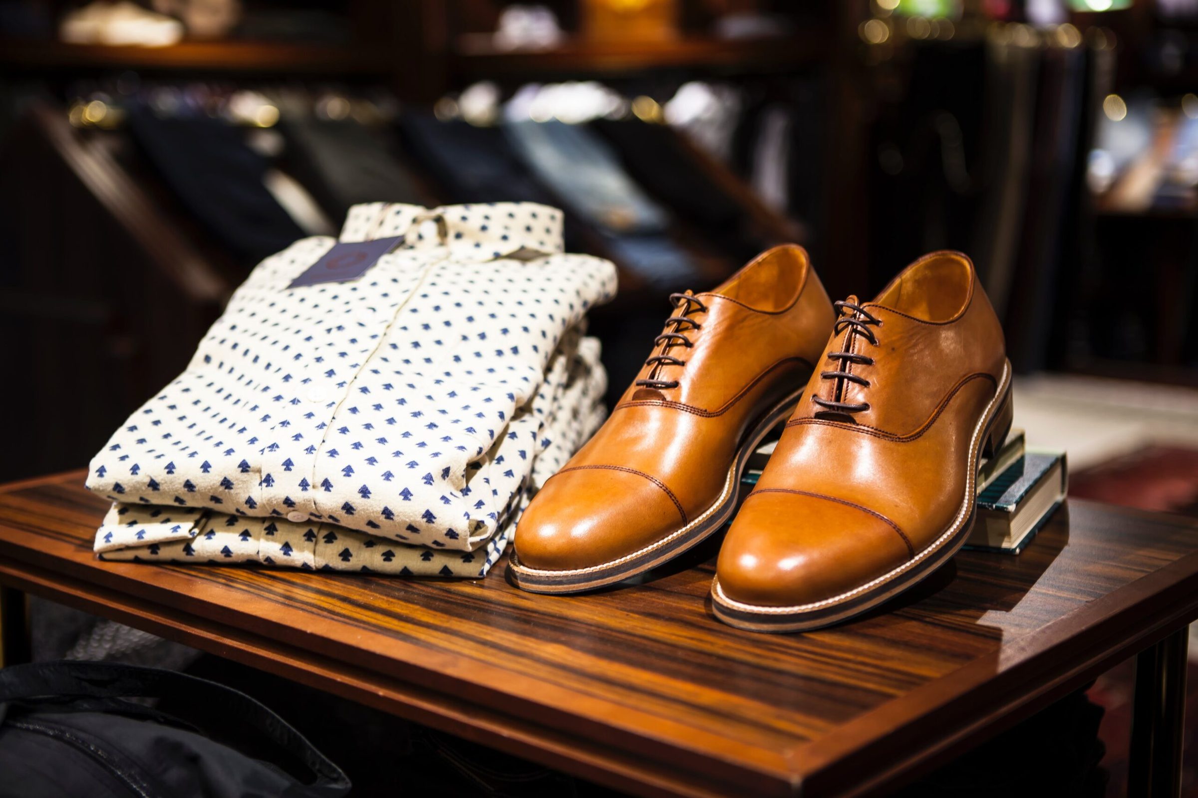 Folded shirts and tan leather brogues laid out on a shop table