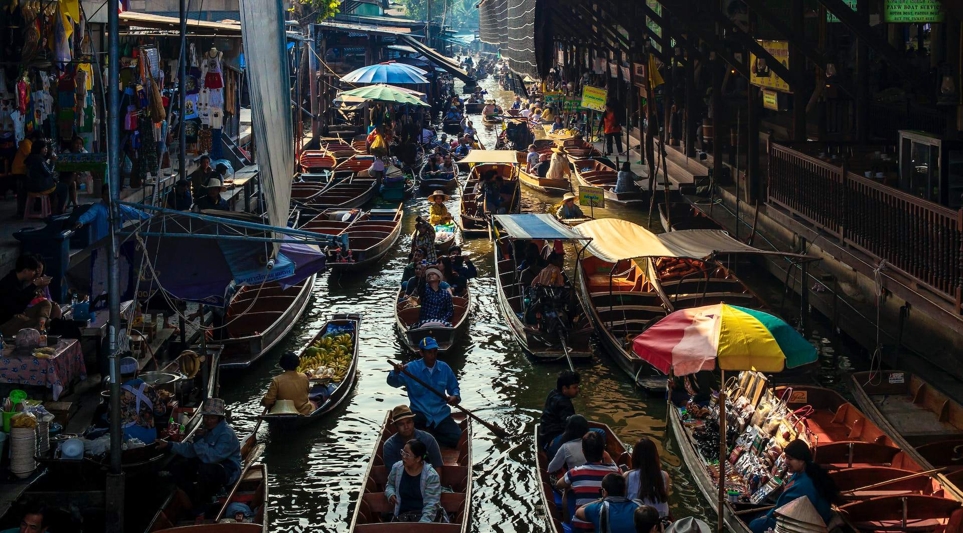 Vendor boats and umbrellas packed along a Thai floating market canal