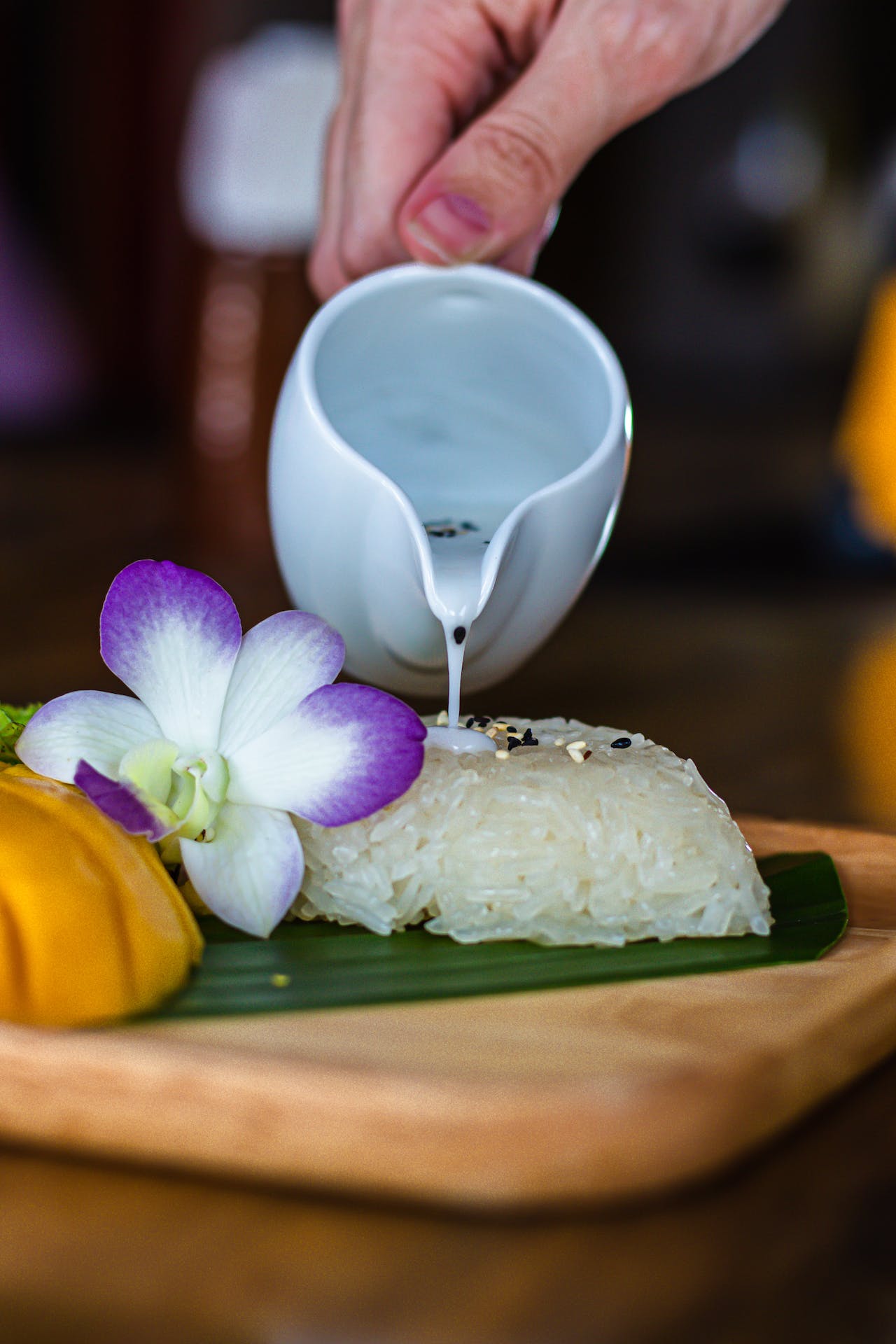 Mango sticky rice with coconut cream and an orchid