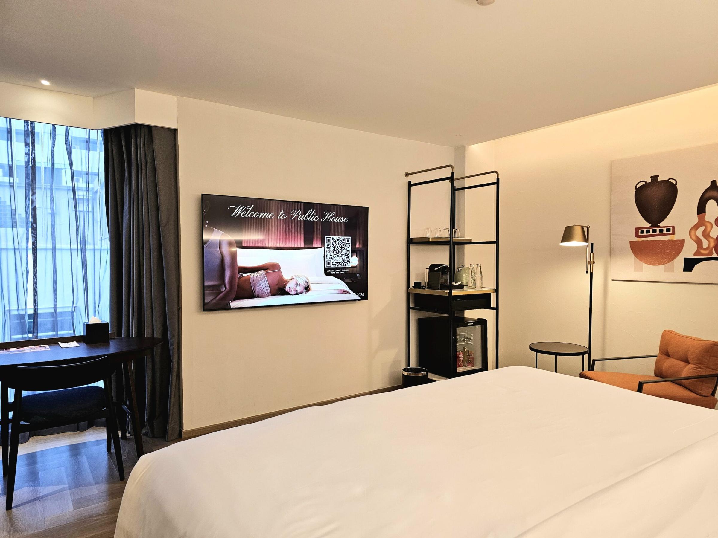 Downtown Room with a 65-inch Smart TV, open shelving, writing desk and an orange armchair