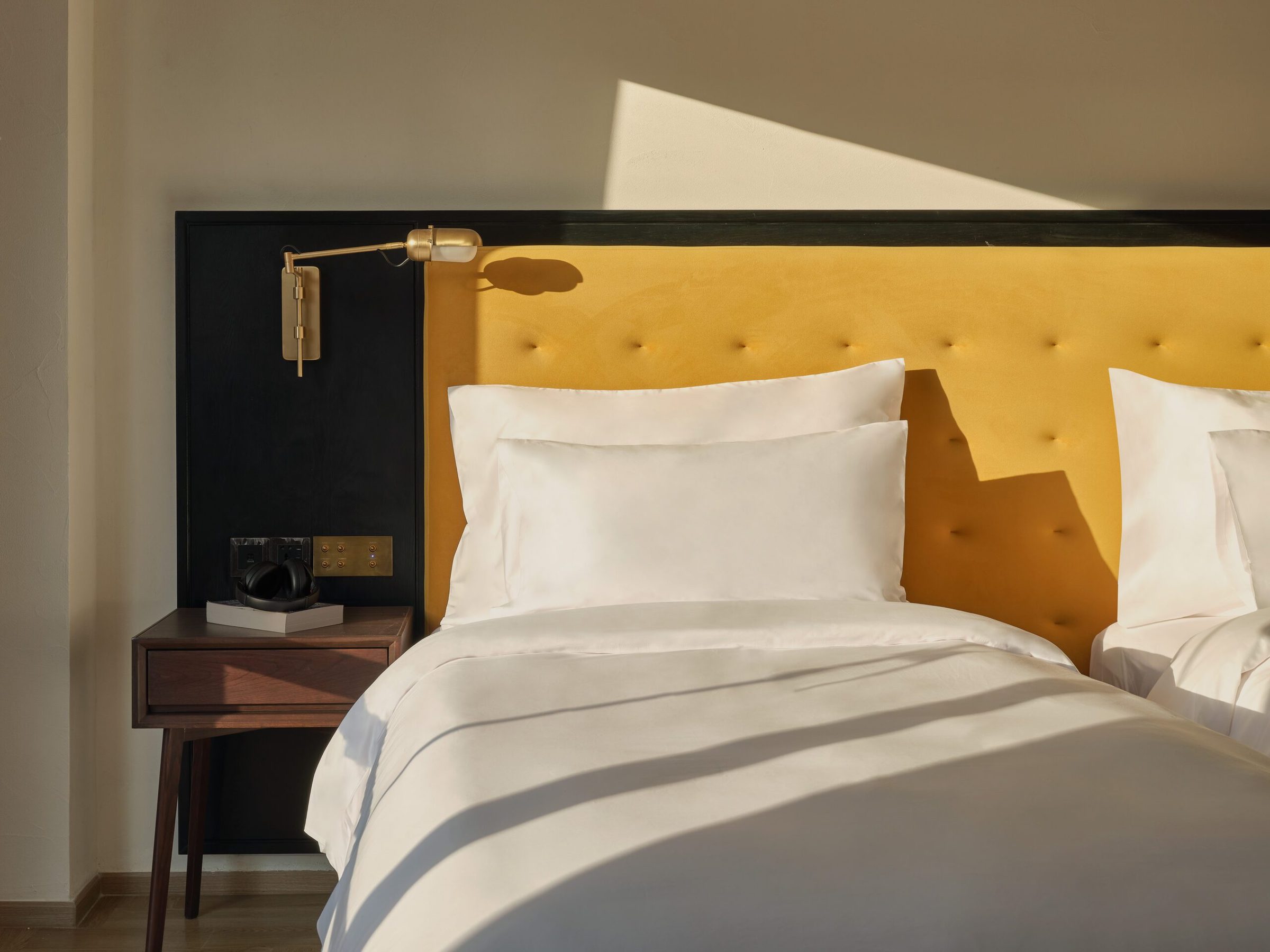 Bed and brass reading light in a Downtown Room at Public House Bangkok