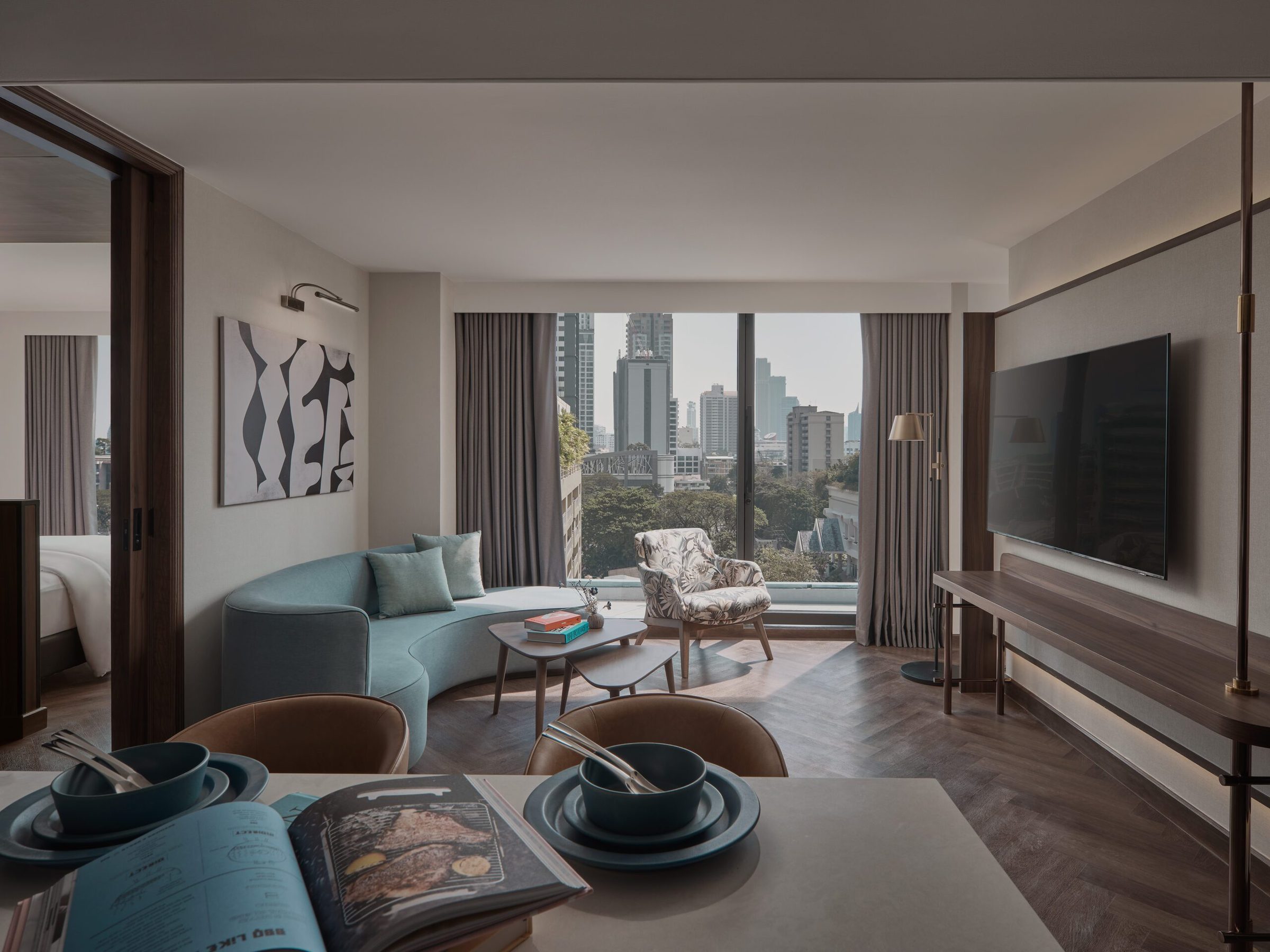 Executive Suite living area at Public House Bangkok with a sofa, armchairs, Smart TV and a window over the city