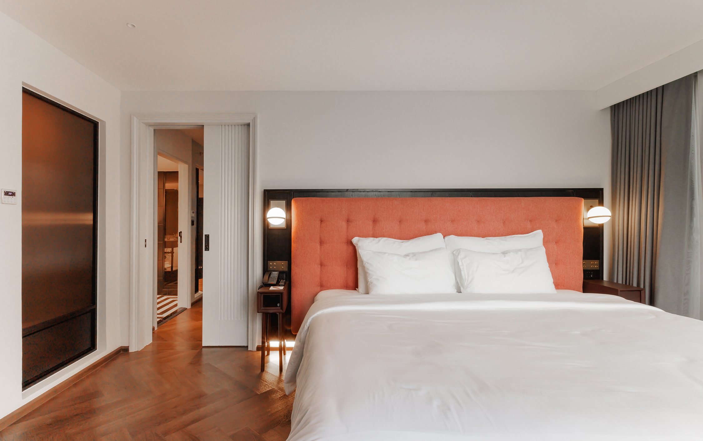 Bedroom of the Two-Bedroom Suite with a coral headboard and the door through to the connecting room