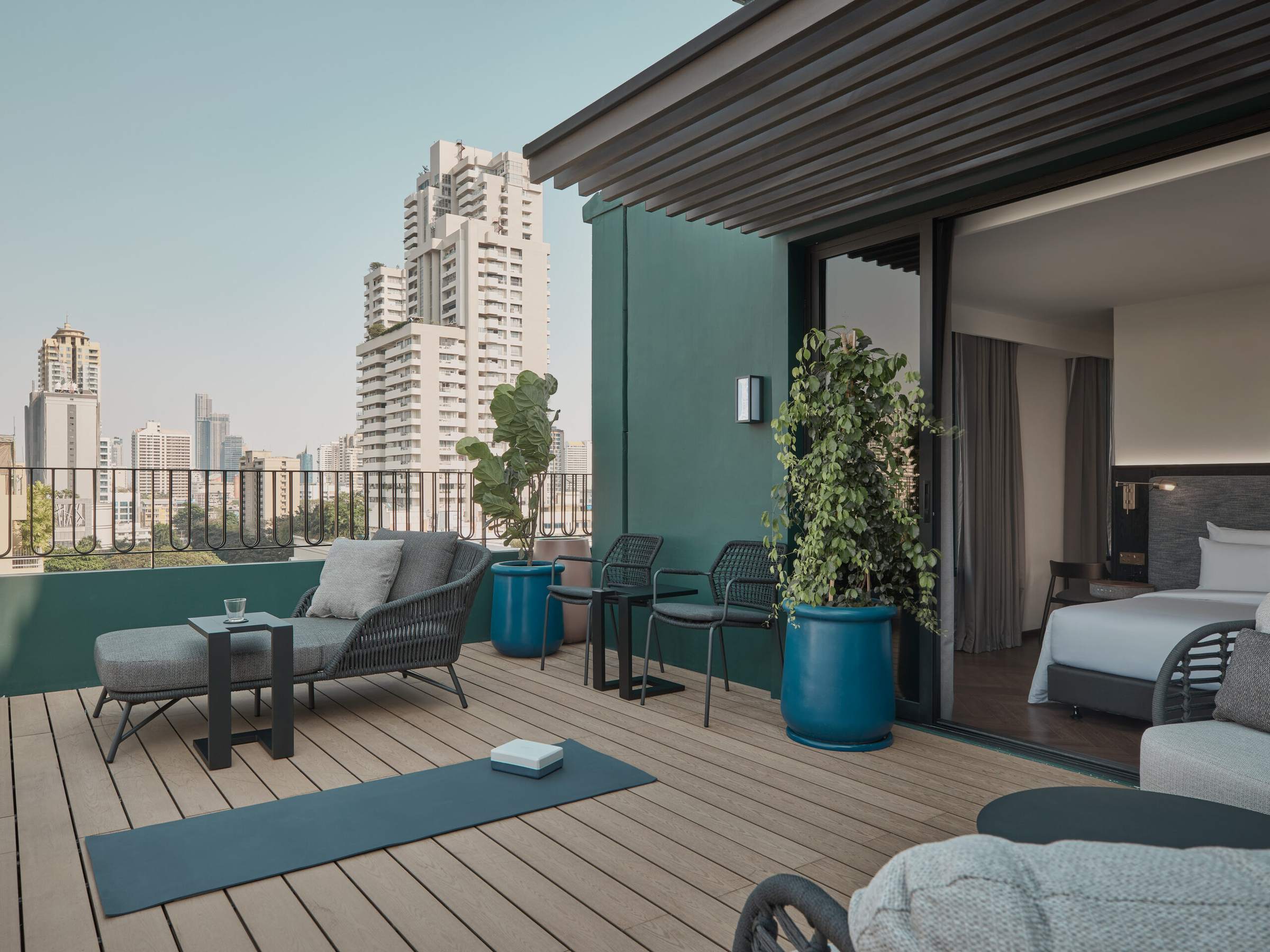 A planted rooftop terrace with a daybed looking across the Bangkok skyline