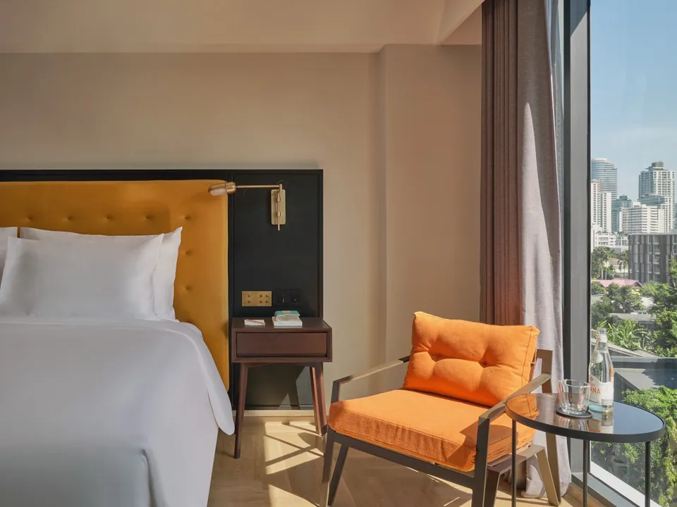 A guest room at Public House Bangkok, its window looking over the Sukhumvit skyline