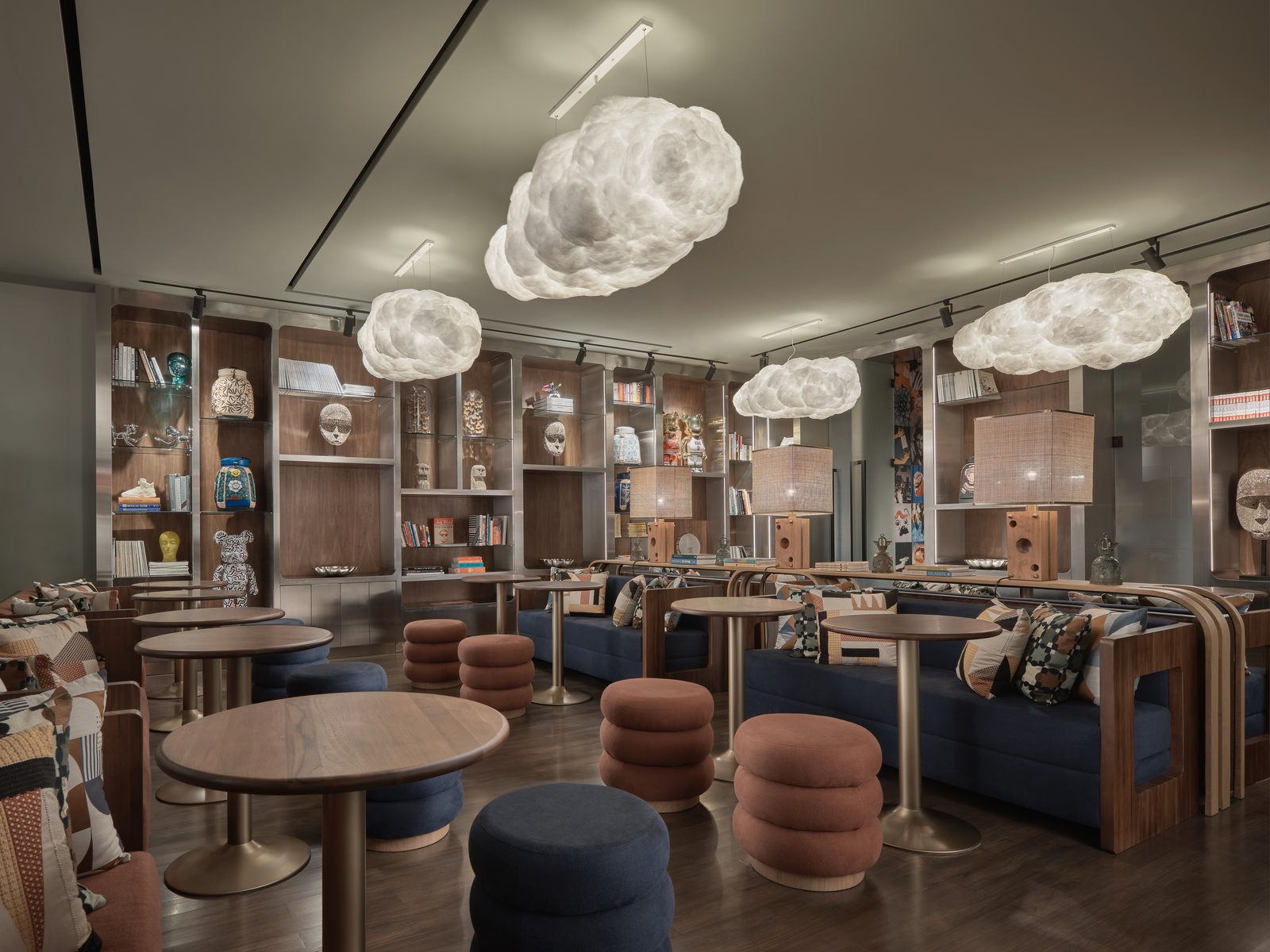 FORUM at Public House Bangkok: cloud-shaped pendant lights over round tables, poufs and banquettes against walls of open shelving