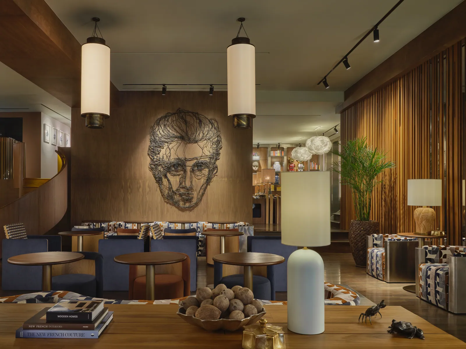 The FORUM floor at Public House Bangkok, with a wire-drawn portrait on the wood-panelled wall, tall pendant lamps and blue banquette seating