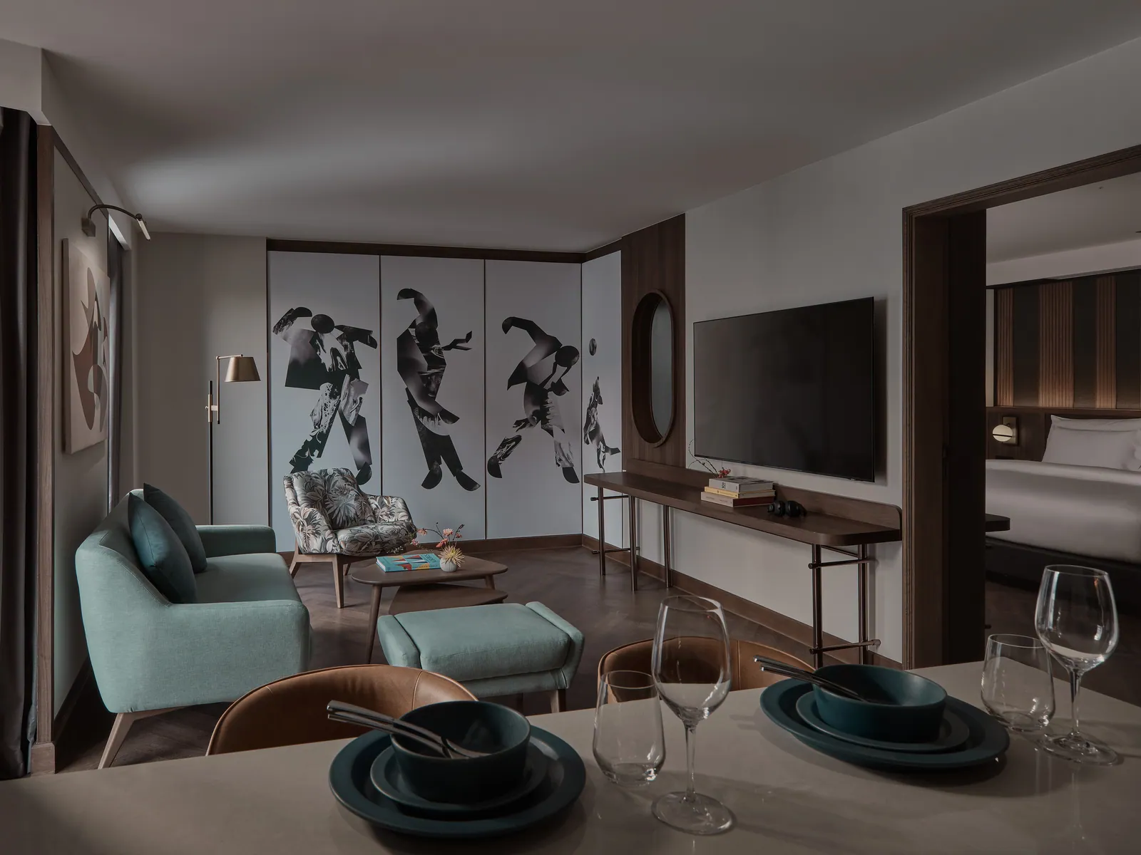 The living room of a suite at Public House Bangkok, with a teal sofa, framed artwork and a low table