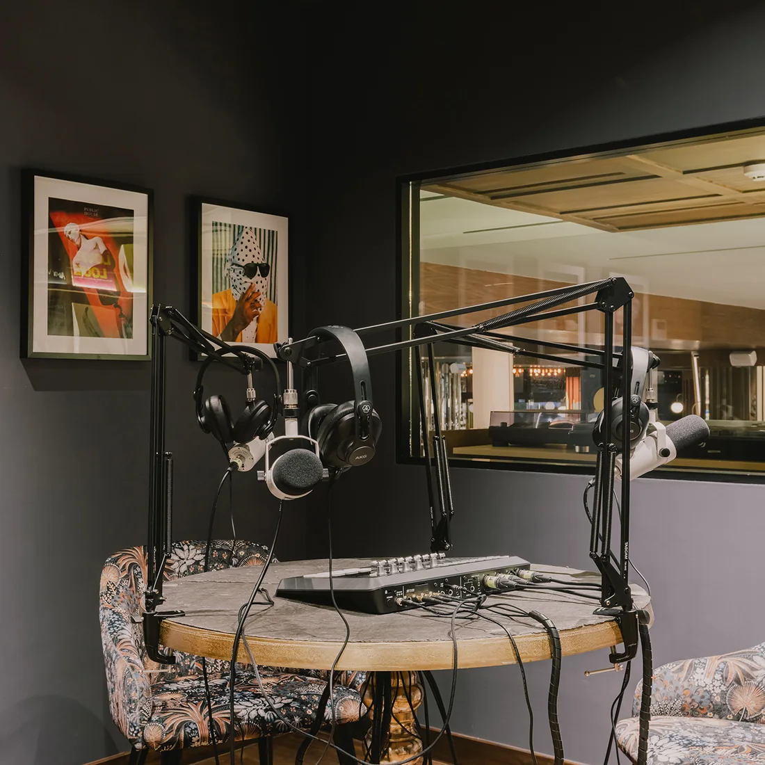 The Podcast Lounge at Public House Bangkok, with microphone booms over a stone table and a window through to the bar