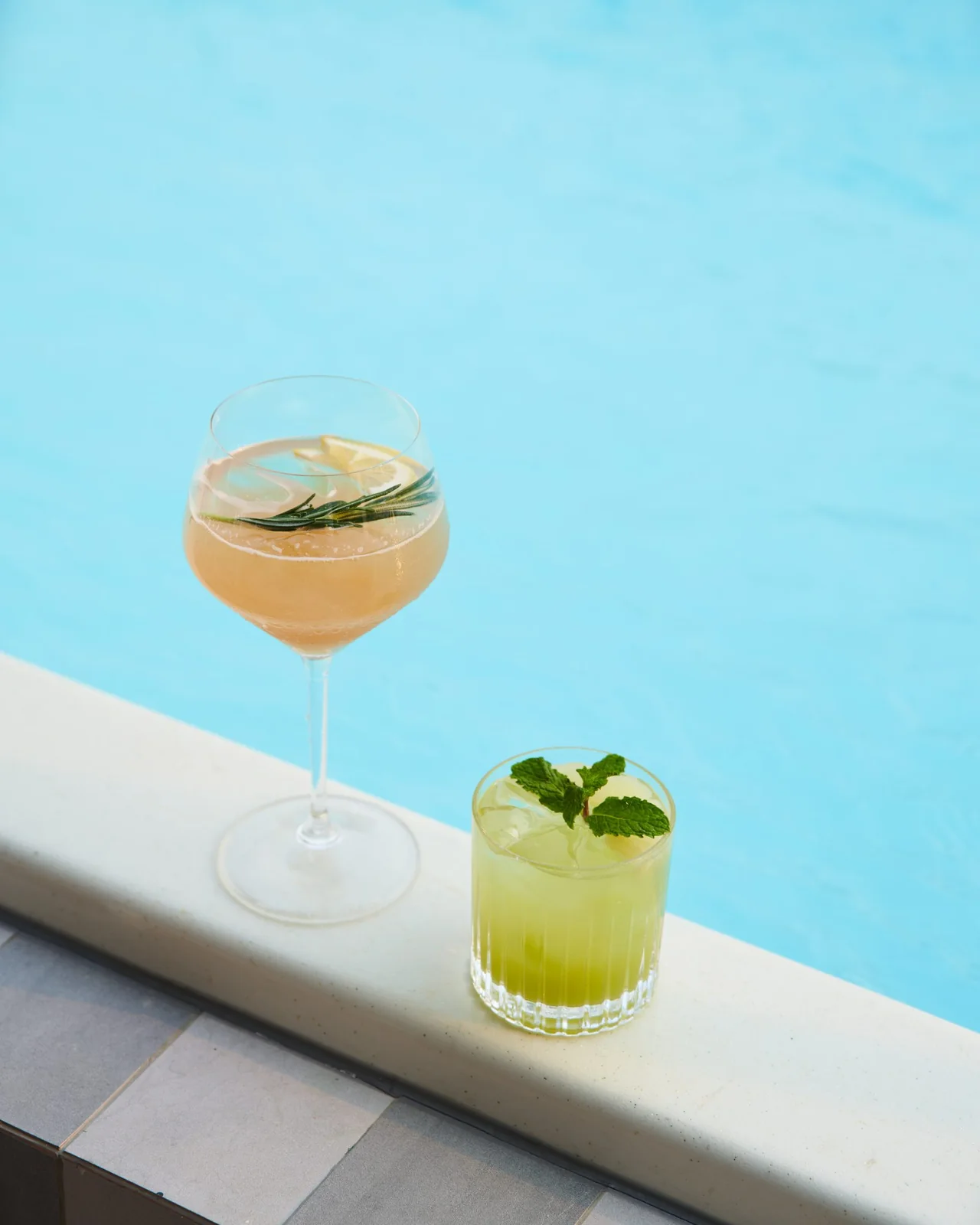 Two cocktails on the tiled edge of the rooftop pool at THE MOOON
