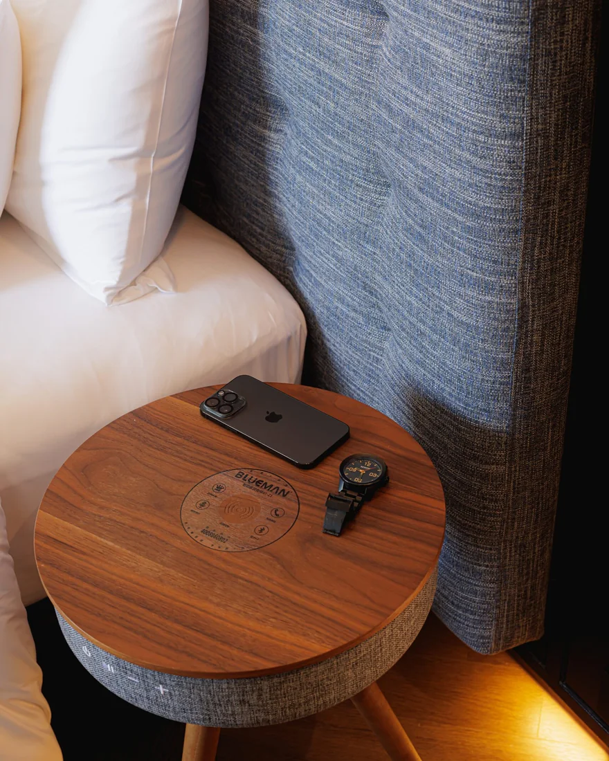 A bedside table beside an upholstered headboard at Public House Bangkok