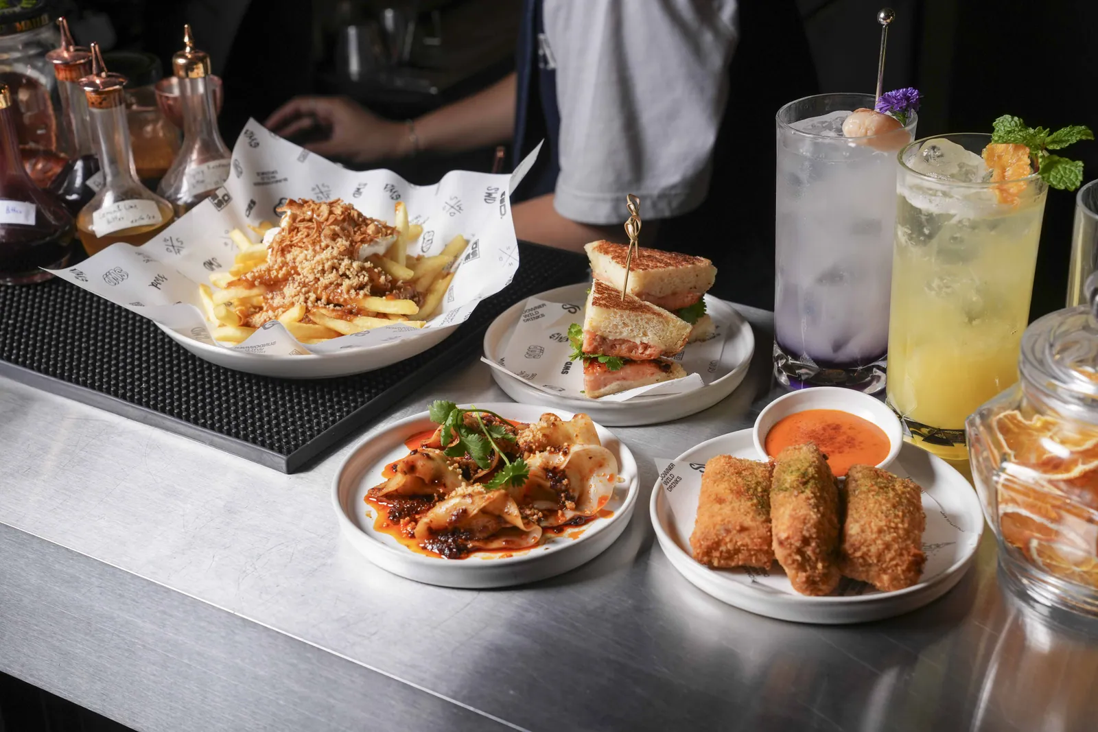Plates and drinks set out along the counter at SWD, the restaurant and bar at Public House Bangkok