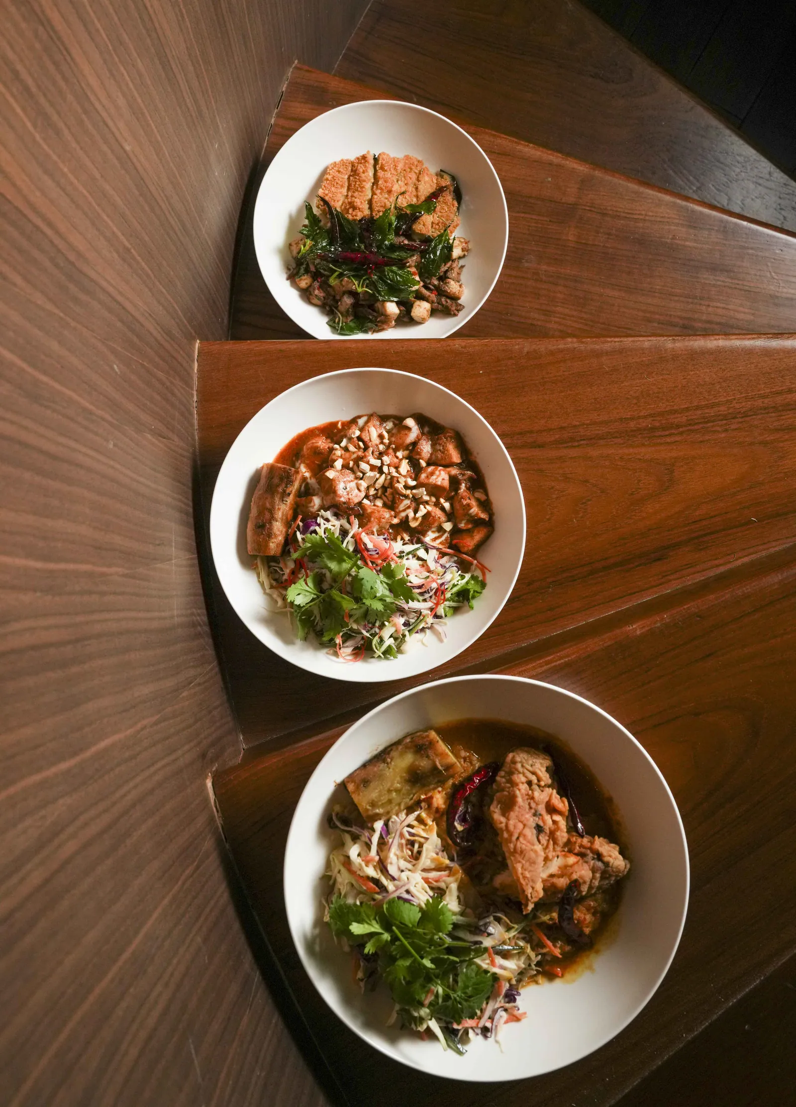 A bowl of leaves and grains on a dark wooden table at SWD, the all-day restaurant at Public House Bangkok