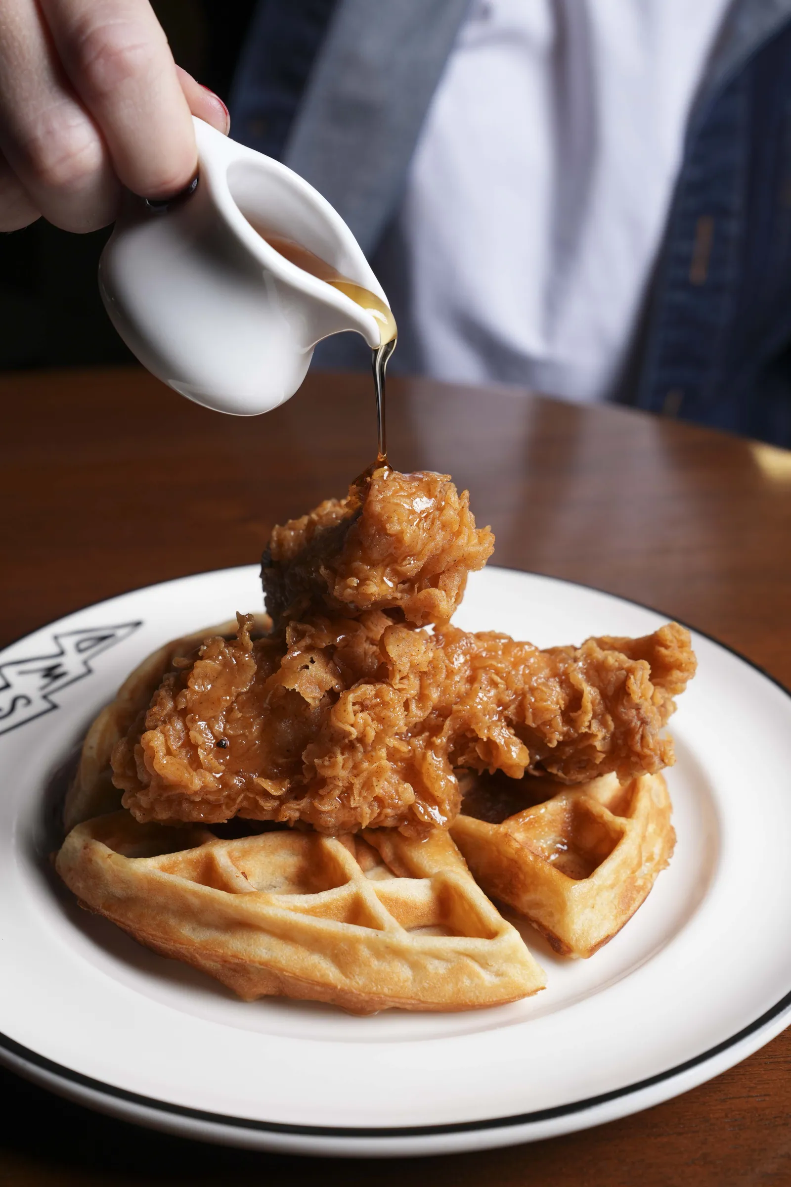Chicken and waffles at SWD Bangkok, maple syrup poured over buttermilk fried chicken